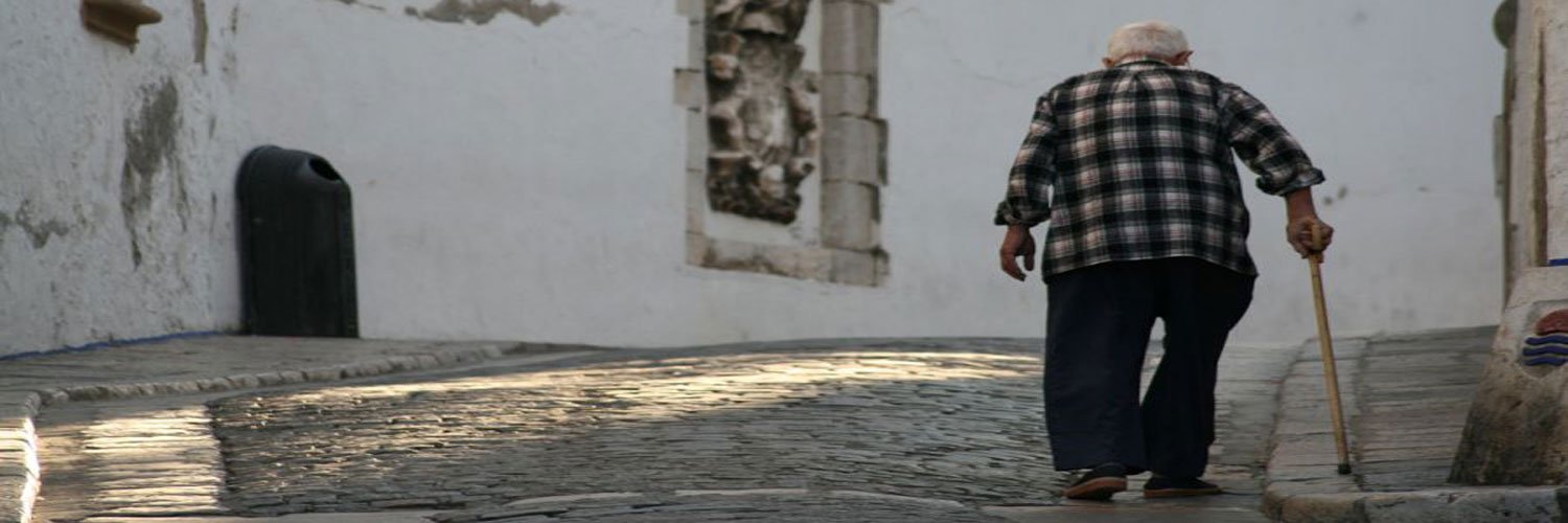 An old man walking up a cobbled road